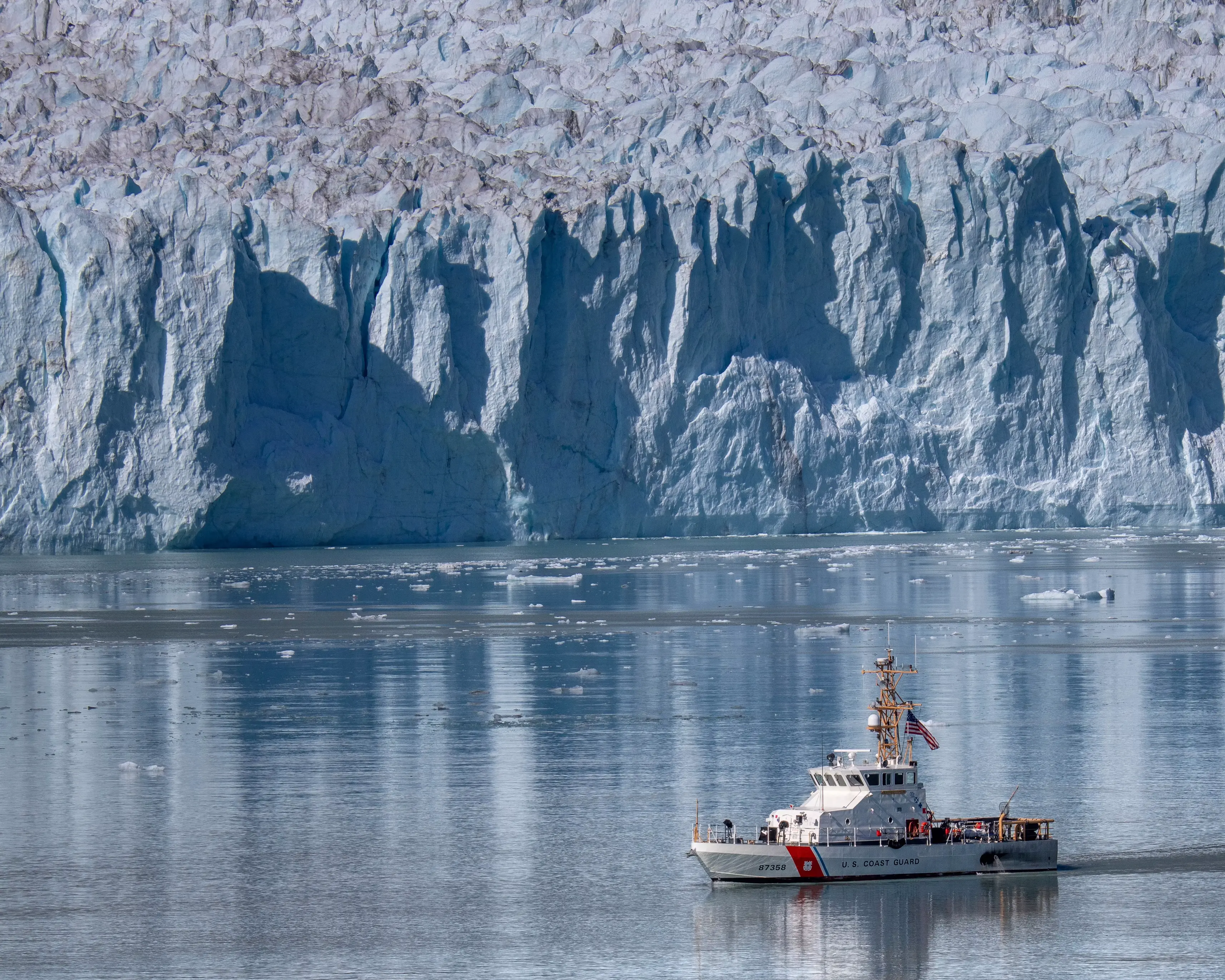 A Coast Guard cutter beneath a tidewater glacier
